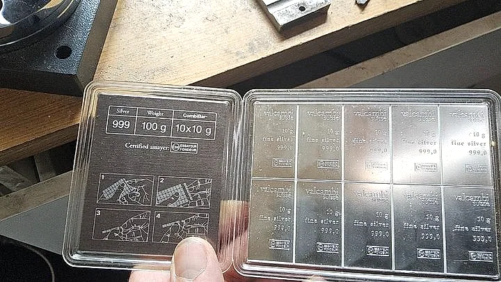 100 g of 999 fine silver Valcambi bullion in its assay case on the bench — the raw material each band is forged from.