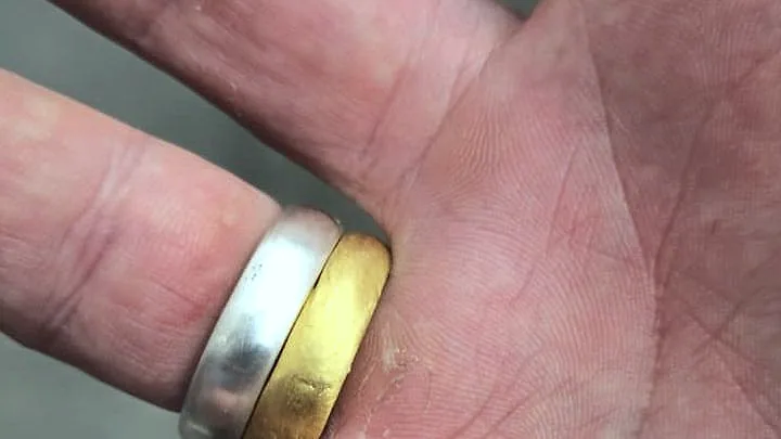 A silver band and a gold band worn together, seen from the palm side. (finished product)