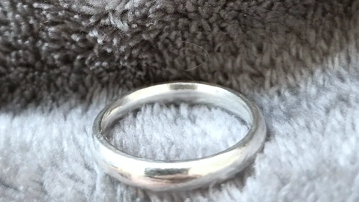 A heavy domed band, side on, catching a broad highlight. (finished product)