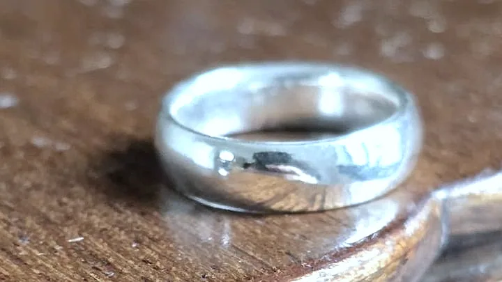 A domed silver band on an old polished wooden surface. (finished product)