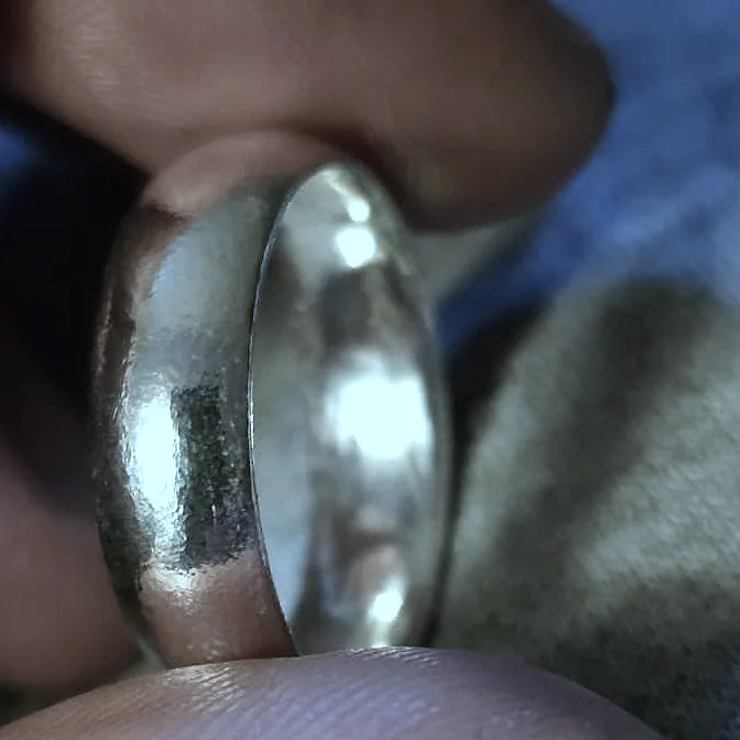 A domed band held close, the join line just visible across the silver. (finished product)