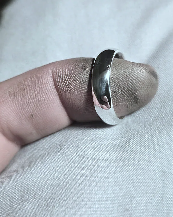 A domed silver band worn against plain cloth. (finished product)