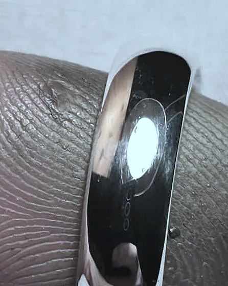 The domed band on a finger, a bright highlight down its face. (finished product)