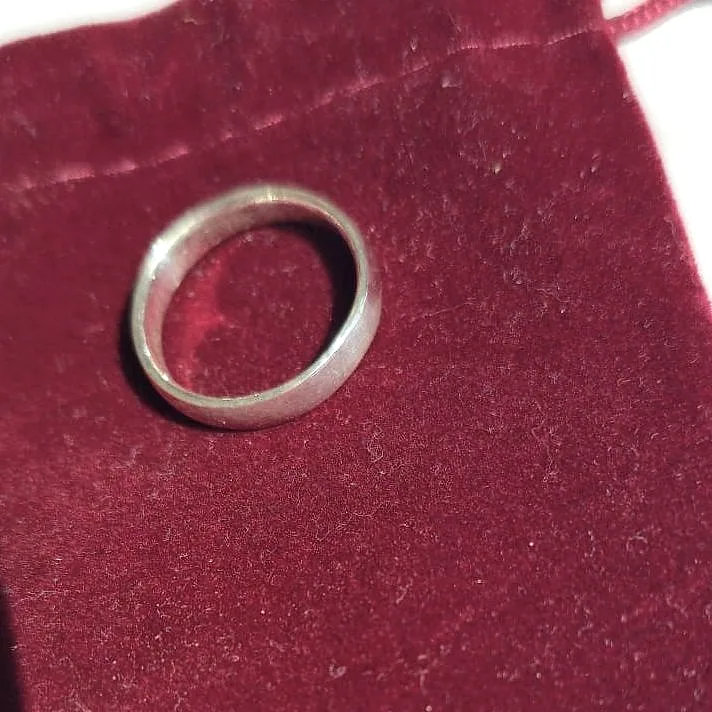 A thin silver band on a deep red velvet pouch. (finished product)