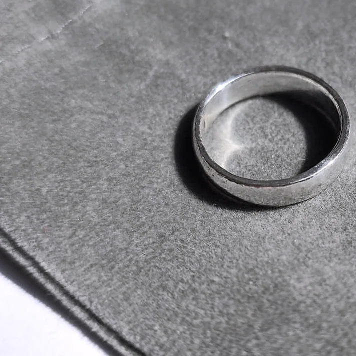 A thin silver band seen from above on a grey suede pouch. (finished product)