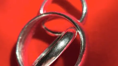Two thin polished bands resting together on red velvet. (finished product)