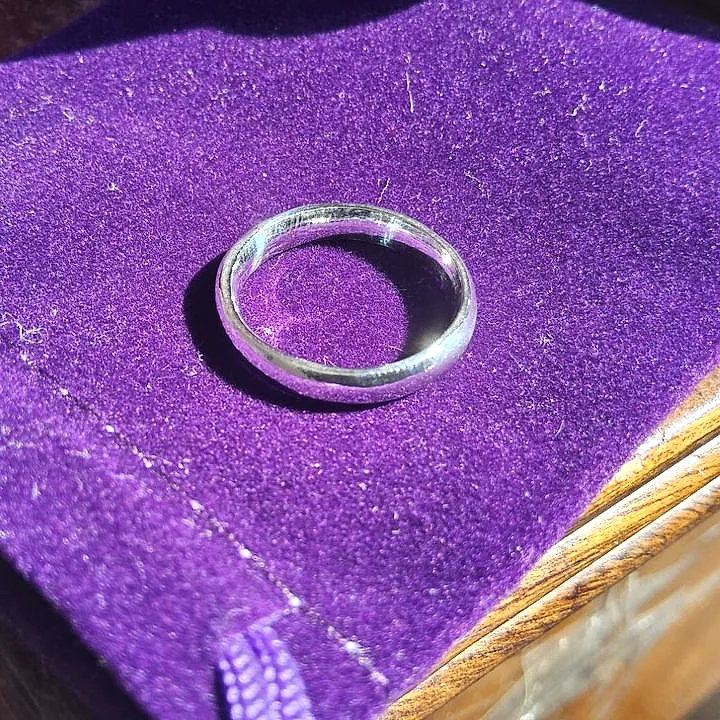 A thin silver band resting on purple velvet, lit from one side. (finished product)