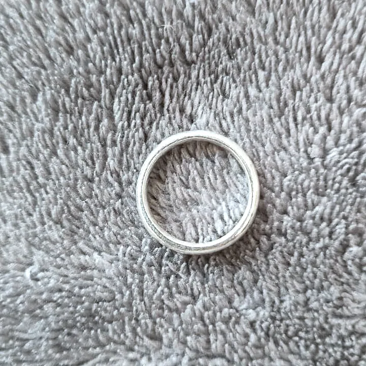 A thin polished band seen from above on a soft grey towel. (finished product)